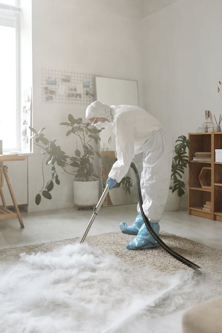 A yellow vacuum cleaner with a black hose is positioned on a patterned area rug in a living room, with the hose extending towards the furniture. To the left, a wooden media console with a black metal 